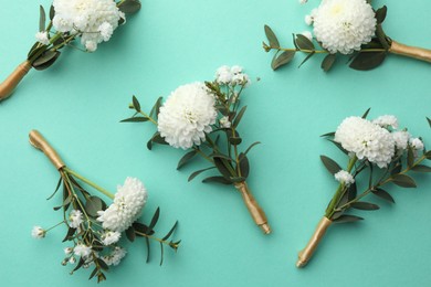 Many stylish boutonnieres on turquoise background, flat lay