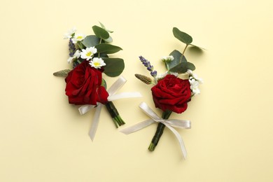 Stylish red boutonnieres on beige background, flat lay