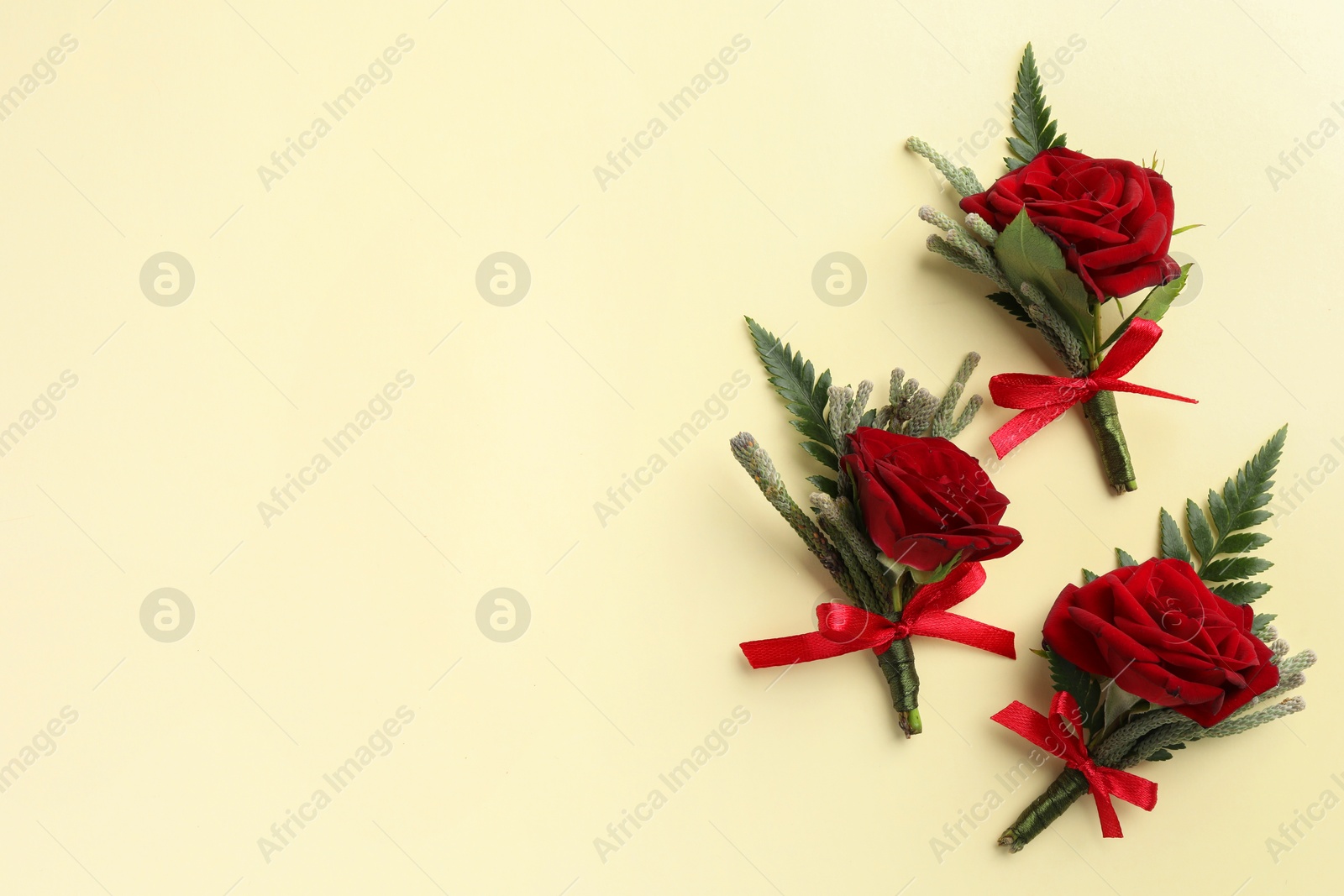 Photo of Many stylish red boutonnieres on beige background, flat lay. Space for text