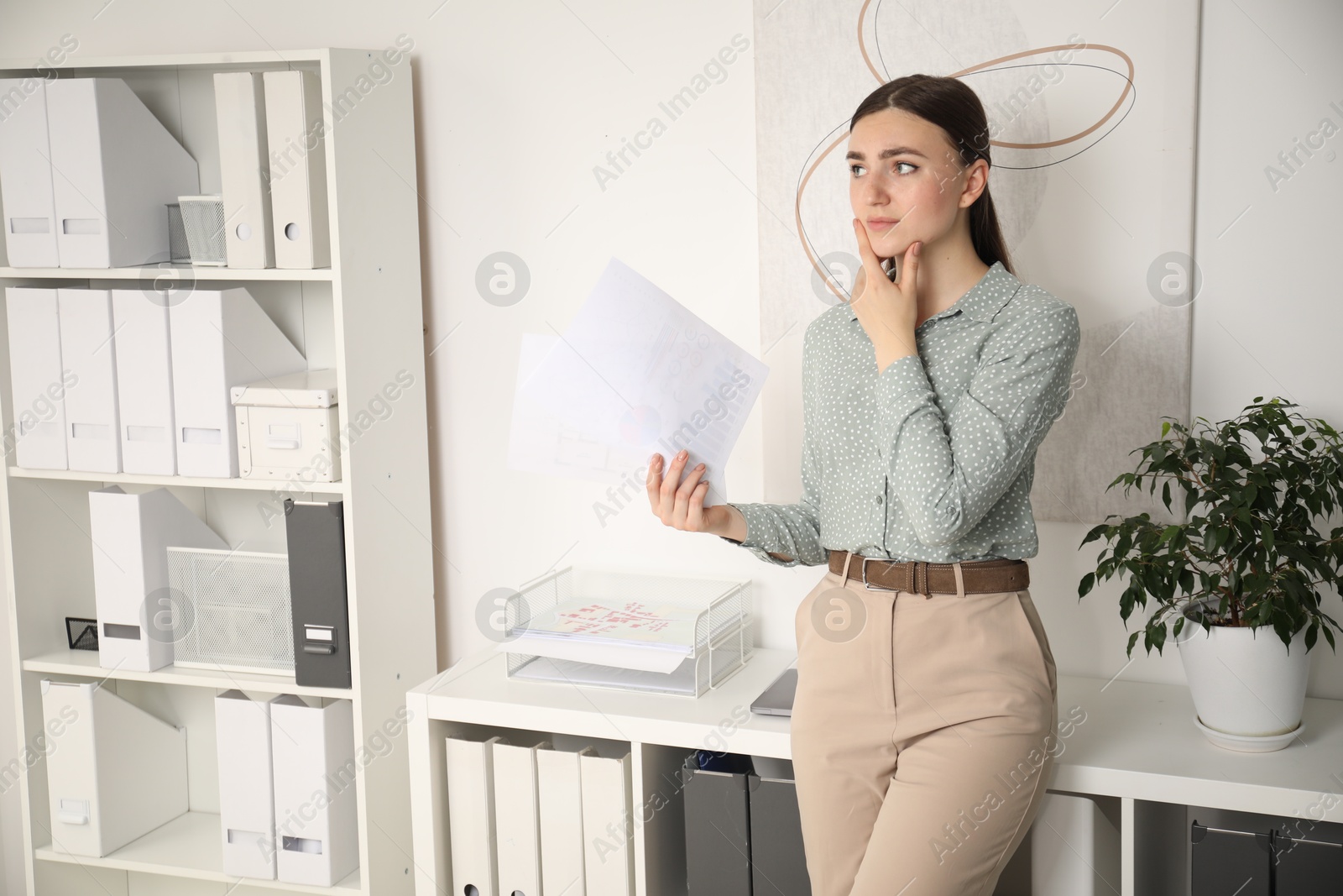 Photo of Embarrassed young woman with documents in office