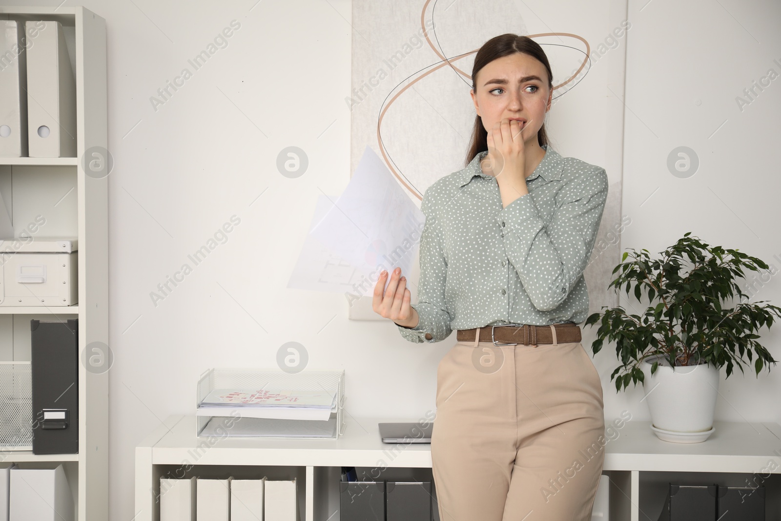 Photo of Embarrassed young woman with documents in office