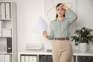 Photo of Embarrassed young woman with documents in office