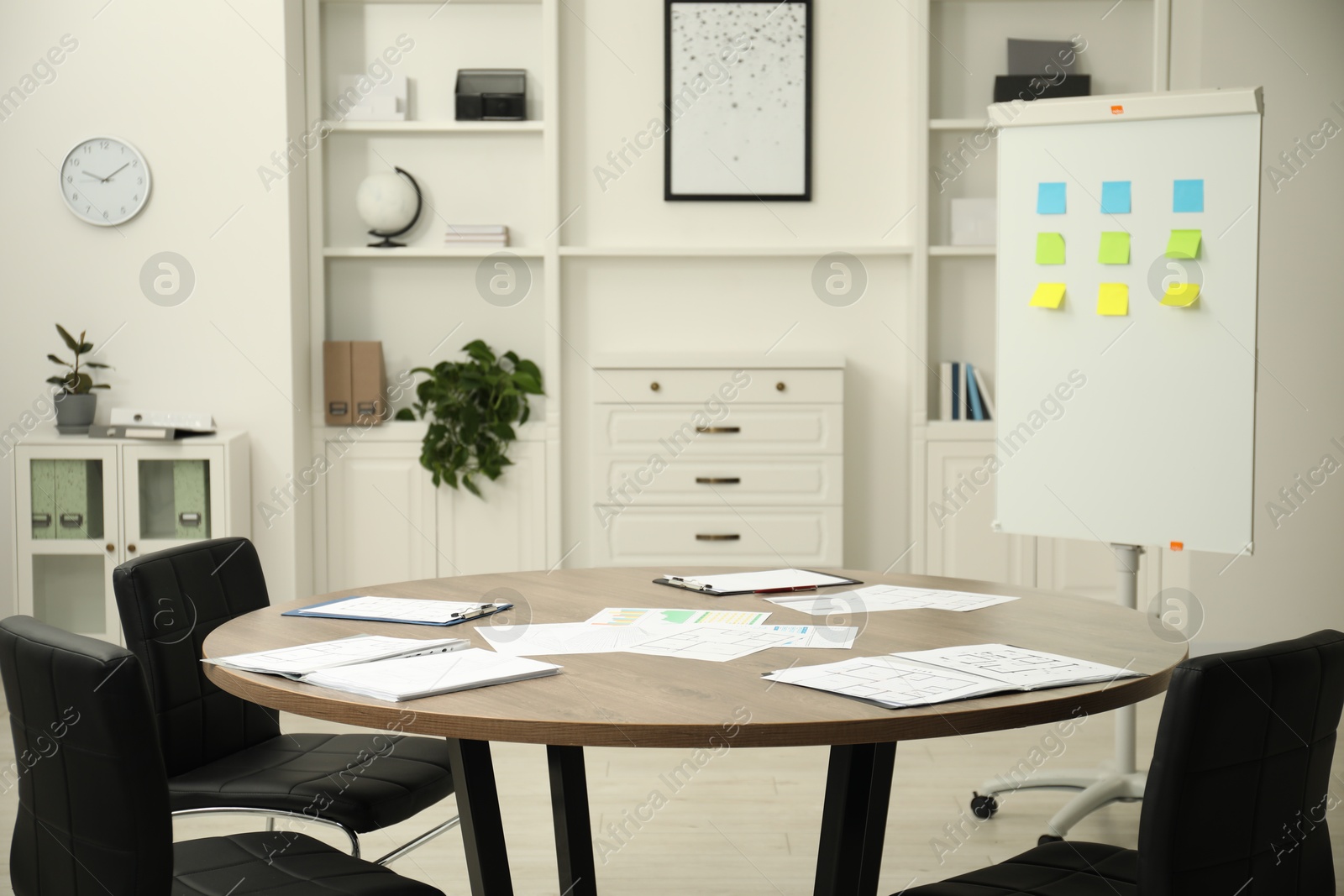 Photo of Wooden table, chairs and white board with sticky notes in conference room