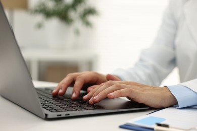 Photo of Doctor using laptop at white table in hospital, closeup