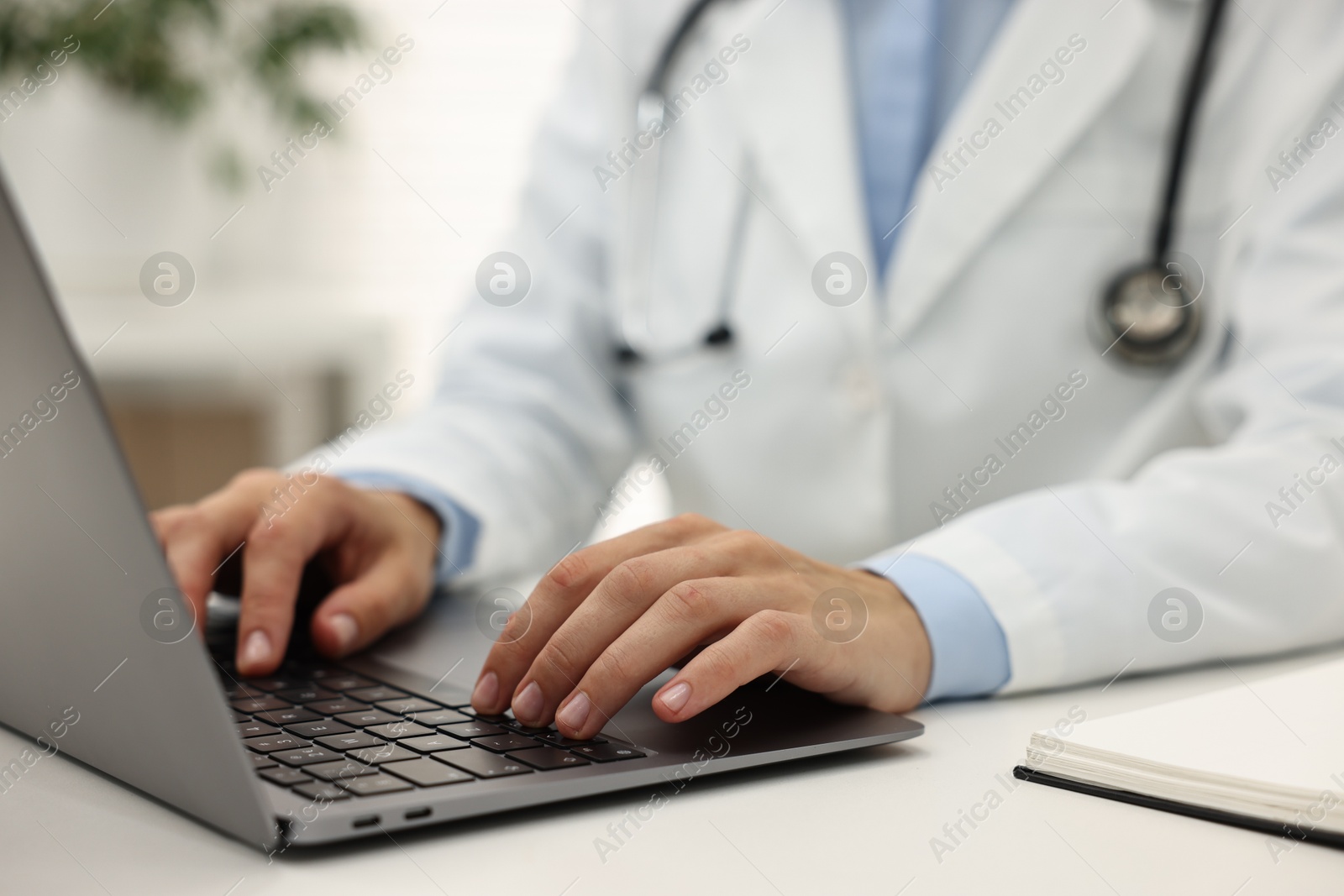 Photo of Doctor using laptop at white table in hospital, closeup