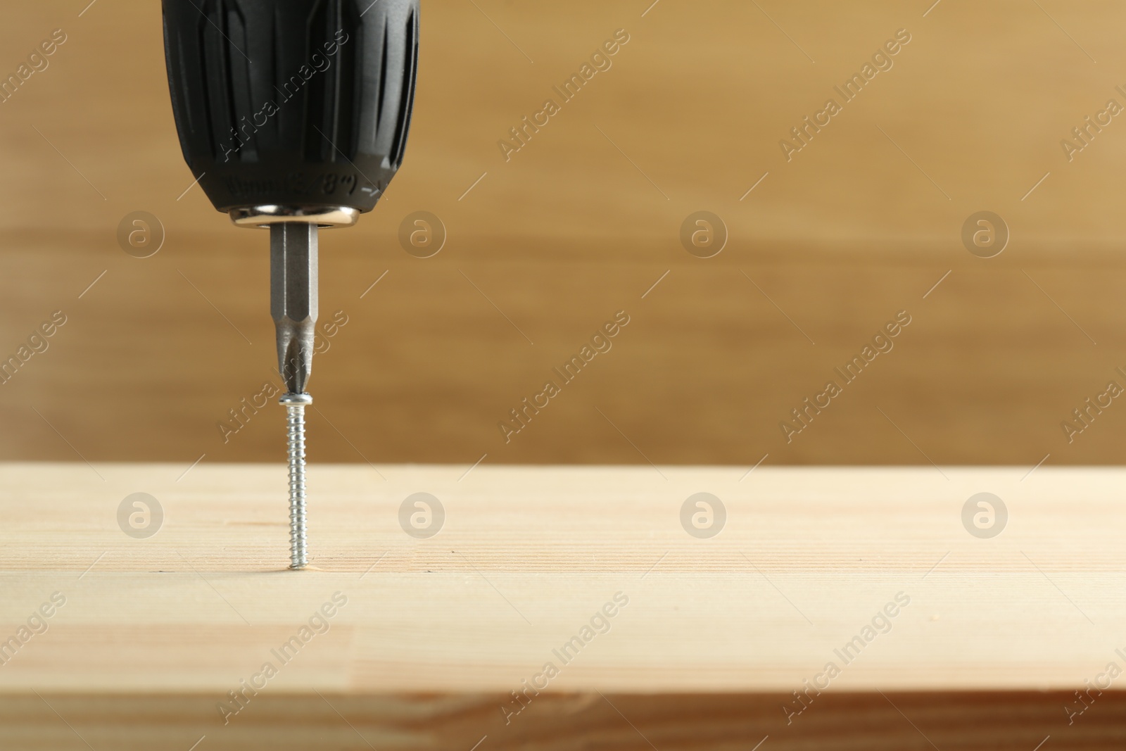 Photo of Screwing screw into wooden plank, closeup. Space for text