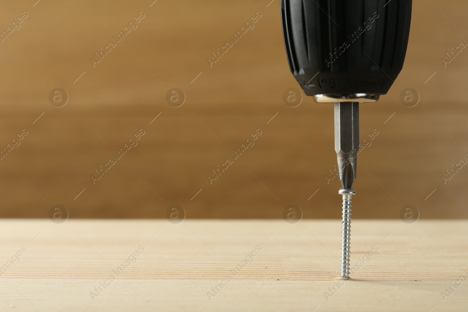 Photo of Screwing screw into wooden plank, closeup. Space for text