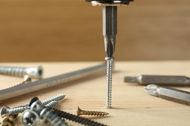 Photo of Screwing screw into wooden plank with bits, closeup