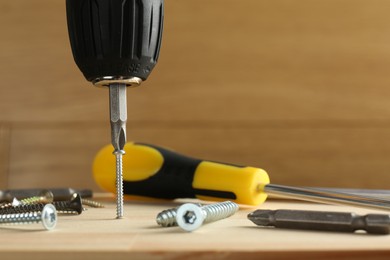 Photo of Screwing screw into wooden plank with tools, closeup