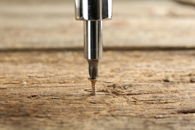 Photo of Screwing screw into wooden surface, closeup view