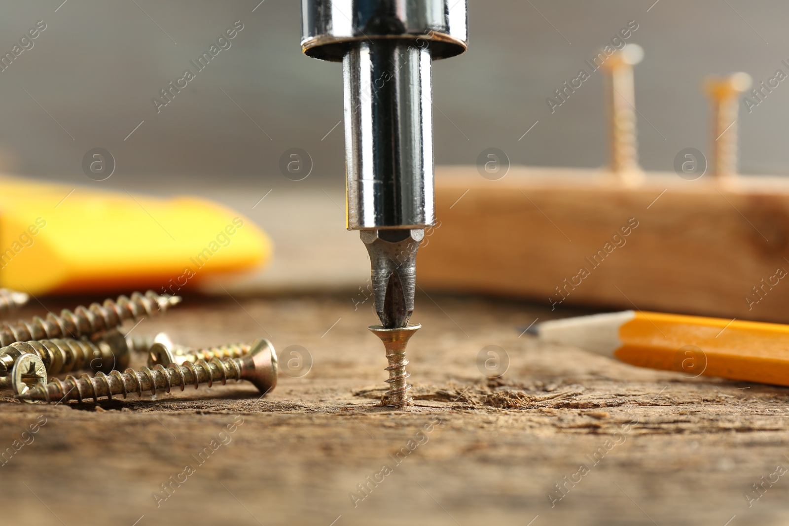 Photo of Screwing screw into wooden surface, closeup view