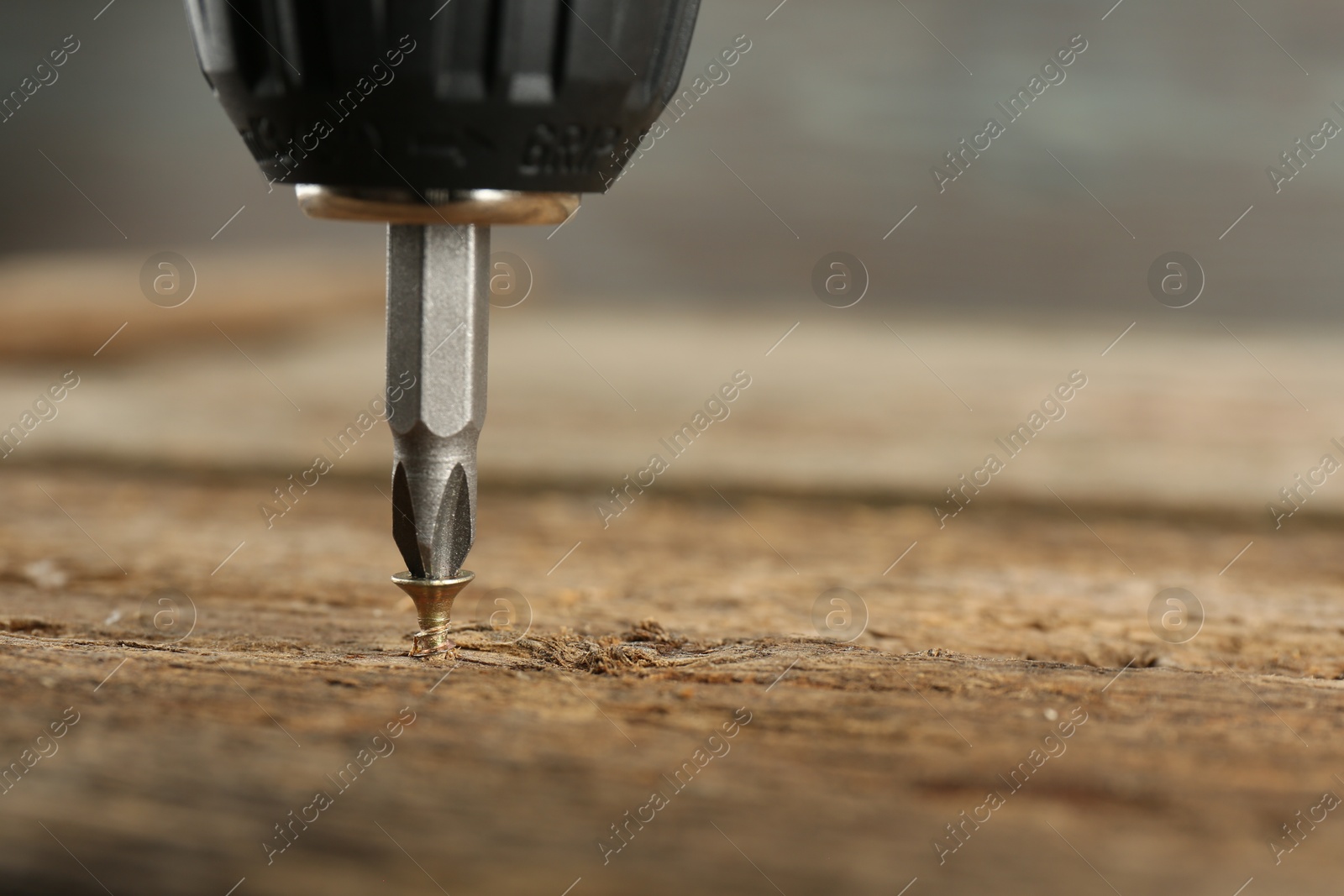 Photo of Screwing screw into wooden surface, closeup. Space for text