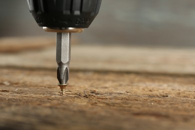 Photo of Screwing screw into wooden surface, closeup. Space for text