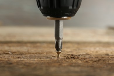 Photo of Screwing screw into wooden surface, closeup view