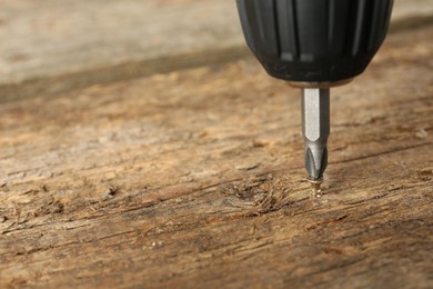 Photo of Screwing screw into wooden surface, closeup. Space for text