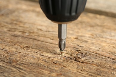 Photo of Screwing screw into wooden surface, closeup view