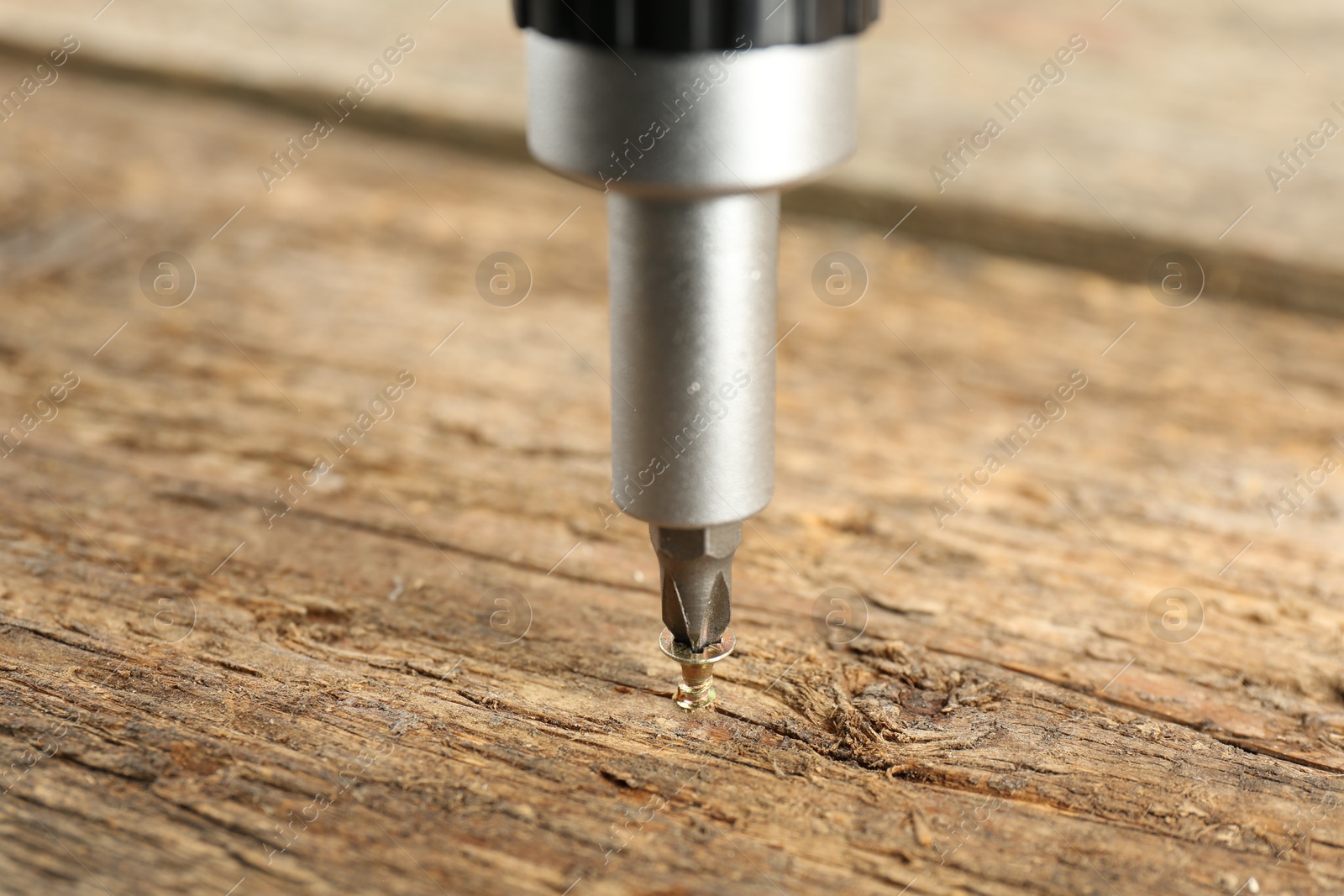 Photo of Screwing screw into wooden surface, closeup view