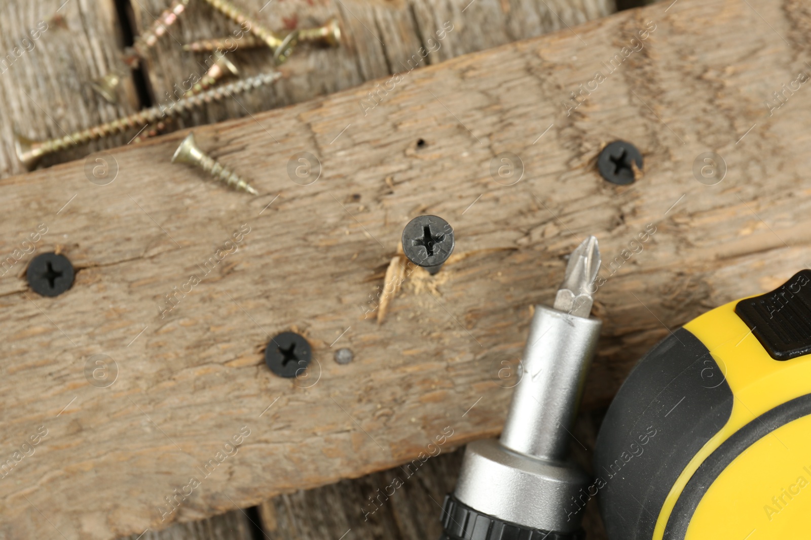 Photo of Screw in wooden plank and equipment on table, top view