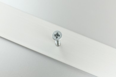 Photo of Metal screw in white panel on light table, above view