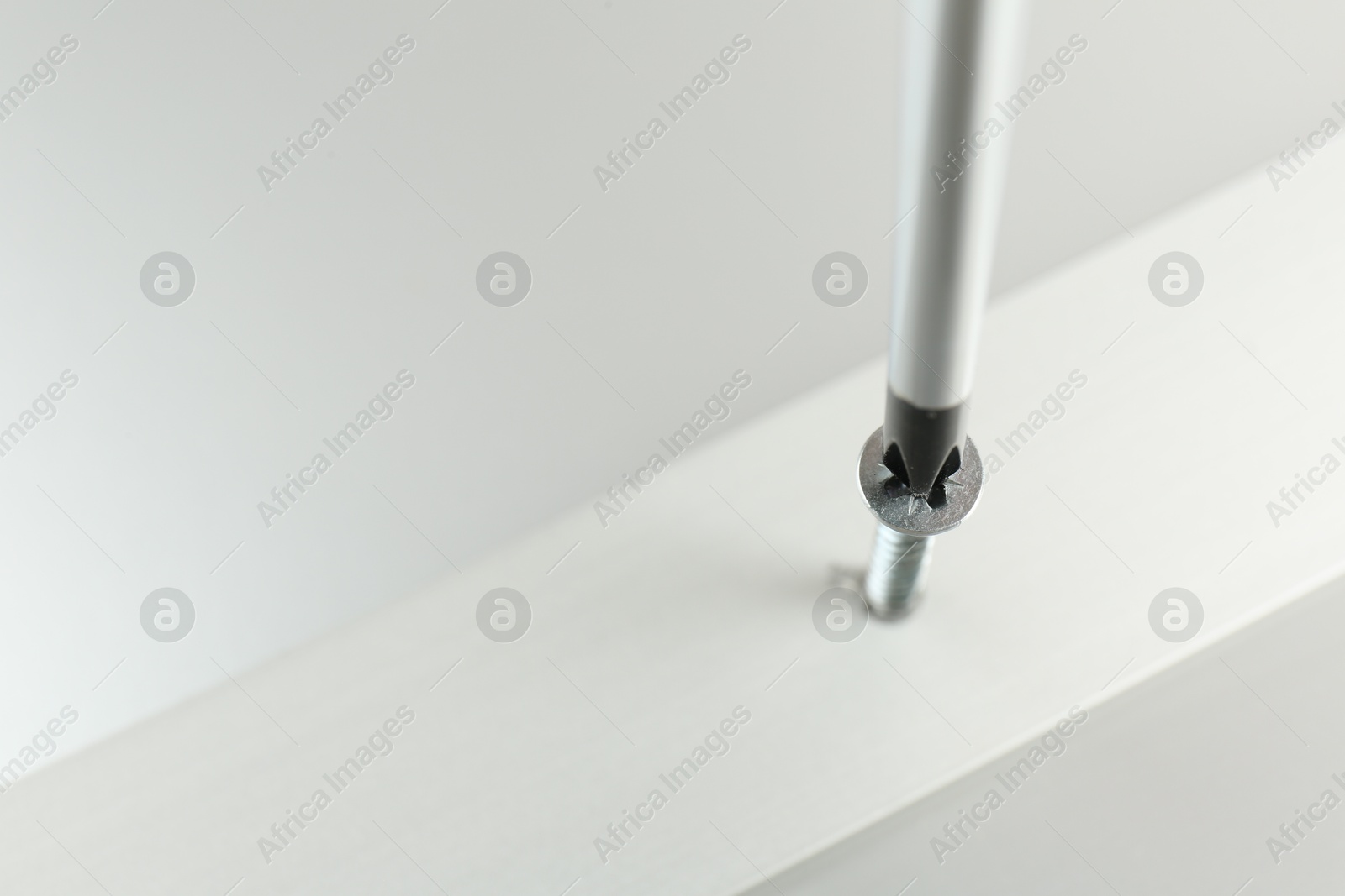 Photo of Screwing screw into white panel at light table, closeup. Space for text