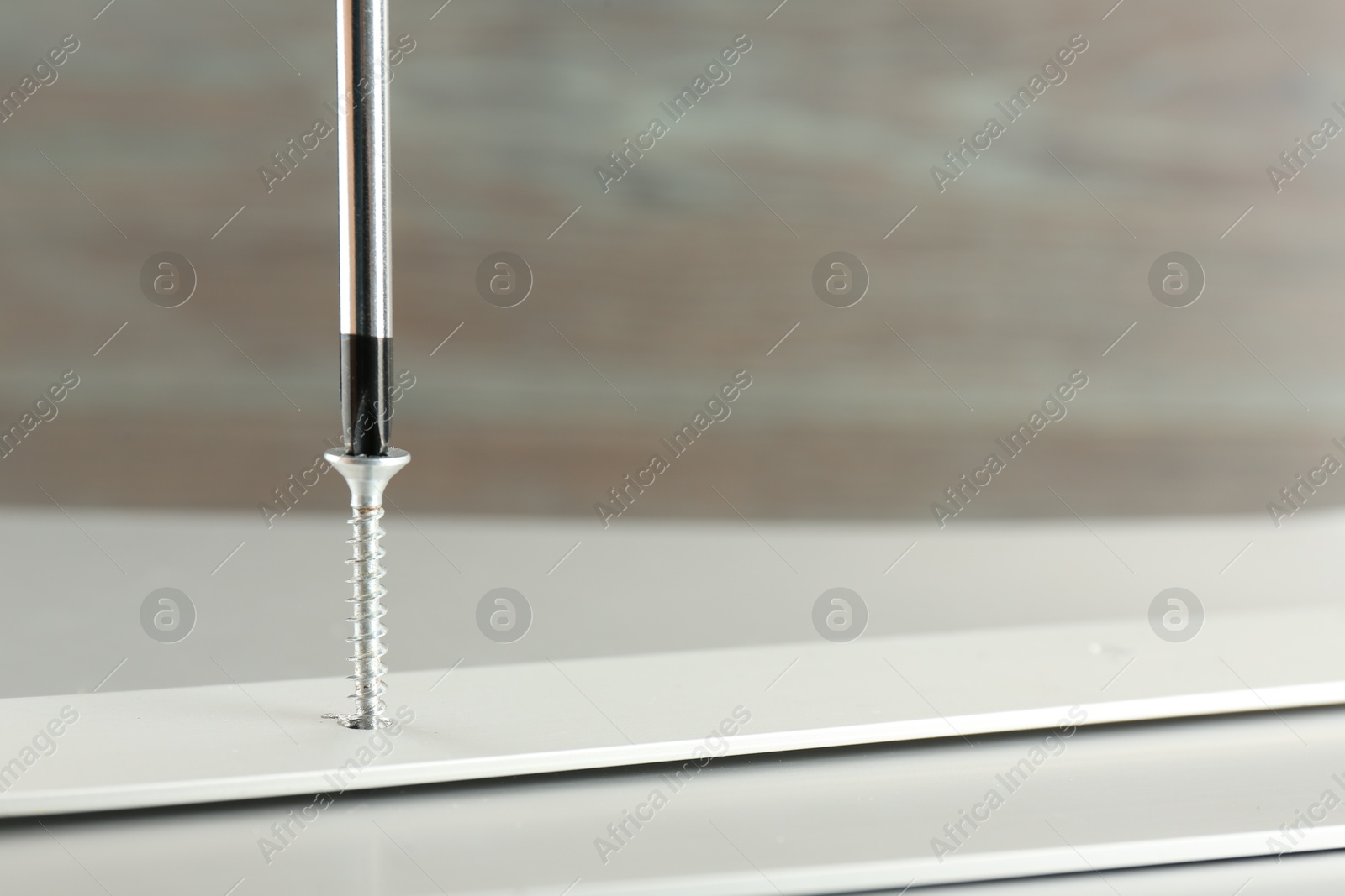 Photo of Screwing screw into white panel at light table, closeup. Space for text