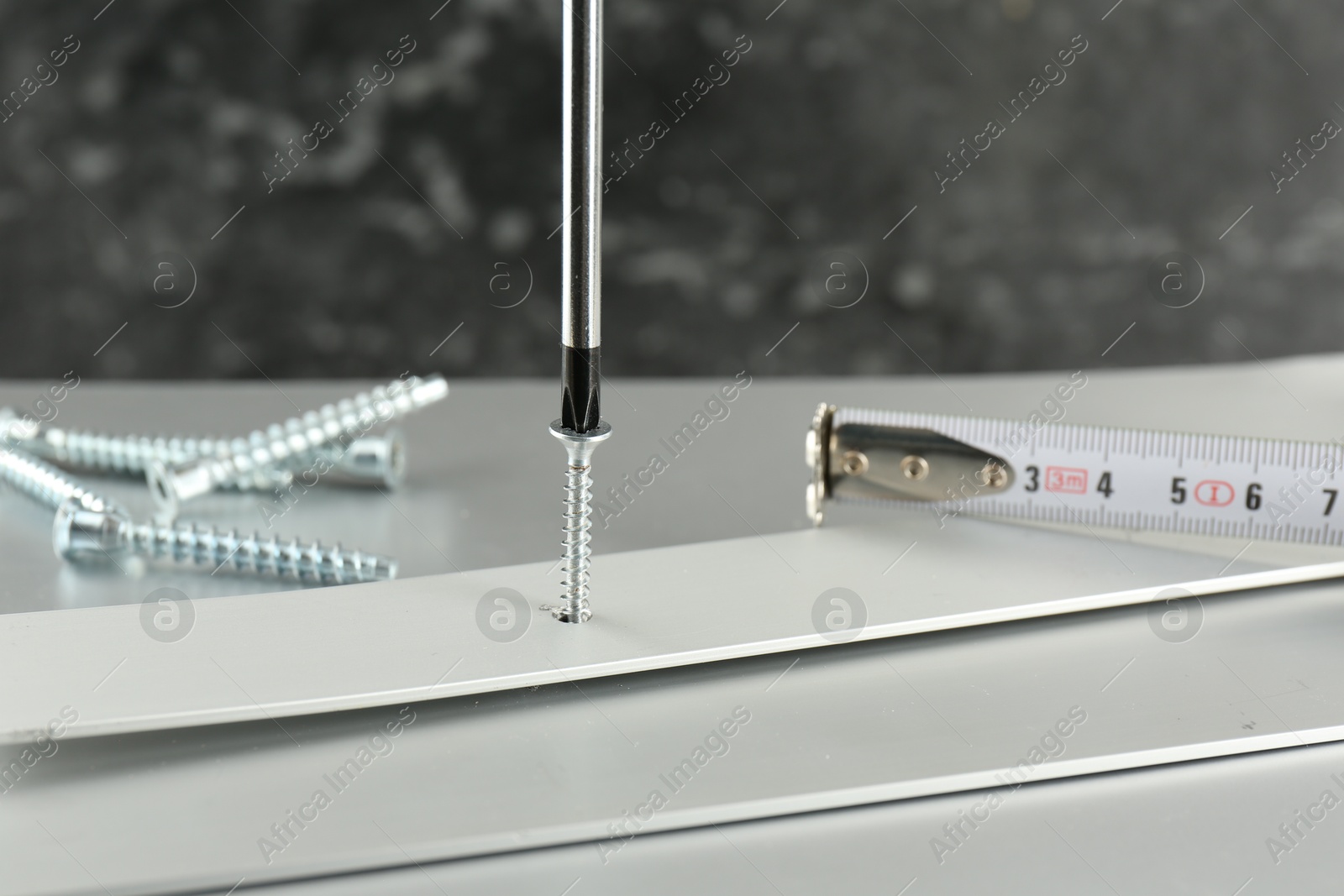 Photo of Screwing screw into white panel at light table, closeup