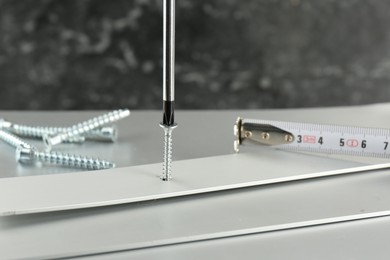 Screwing screw into white panel at light table, closeup