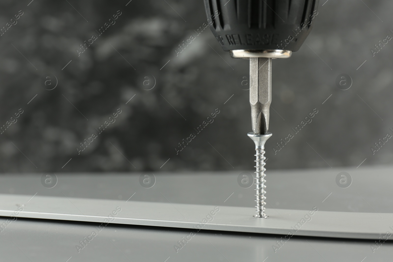 Photo of Screwing screw into white panel at light table, closeup. Space for text