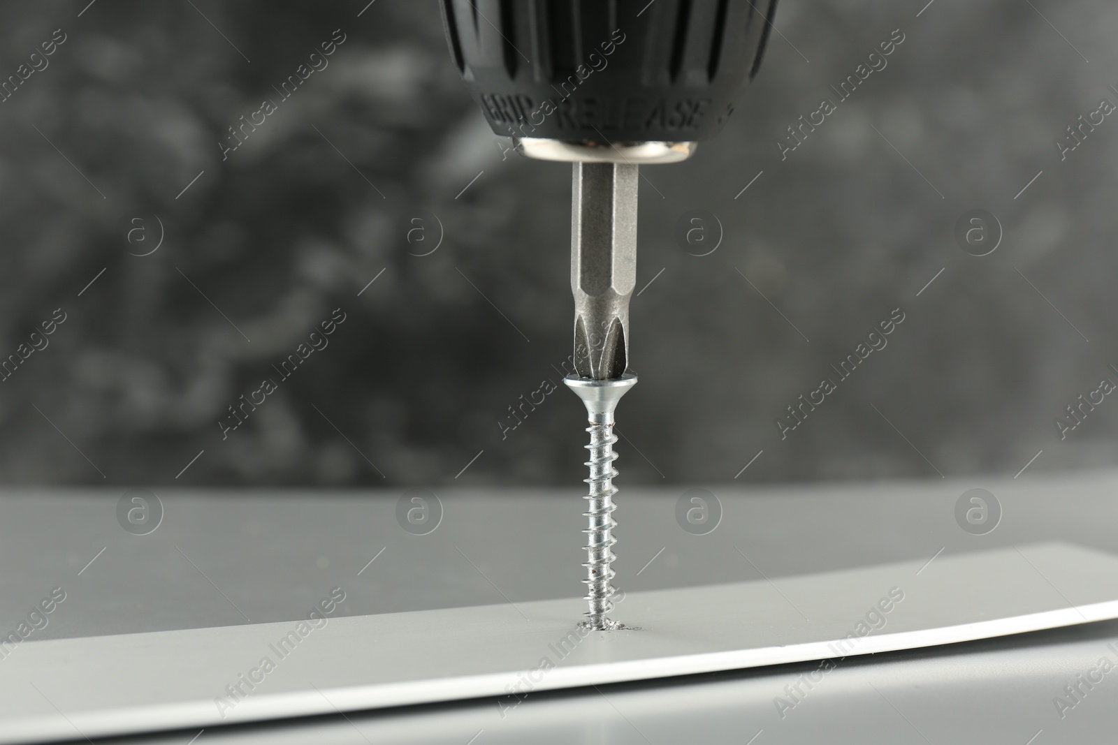 Photo of Screwing screw into white panel at light table, closeup