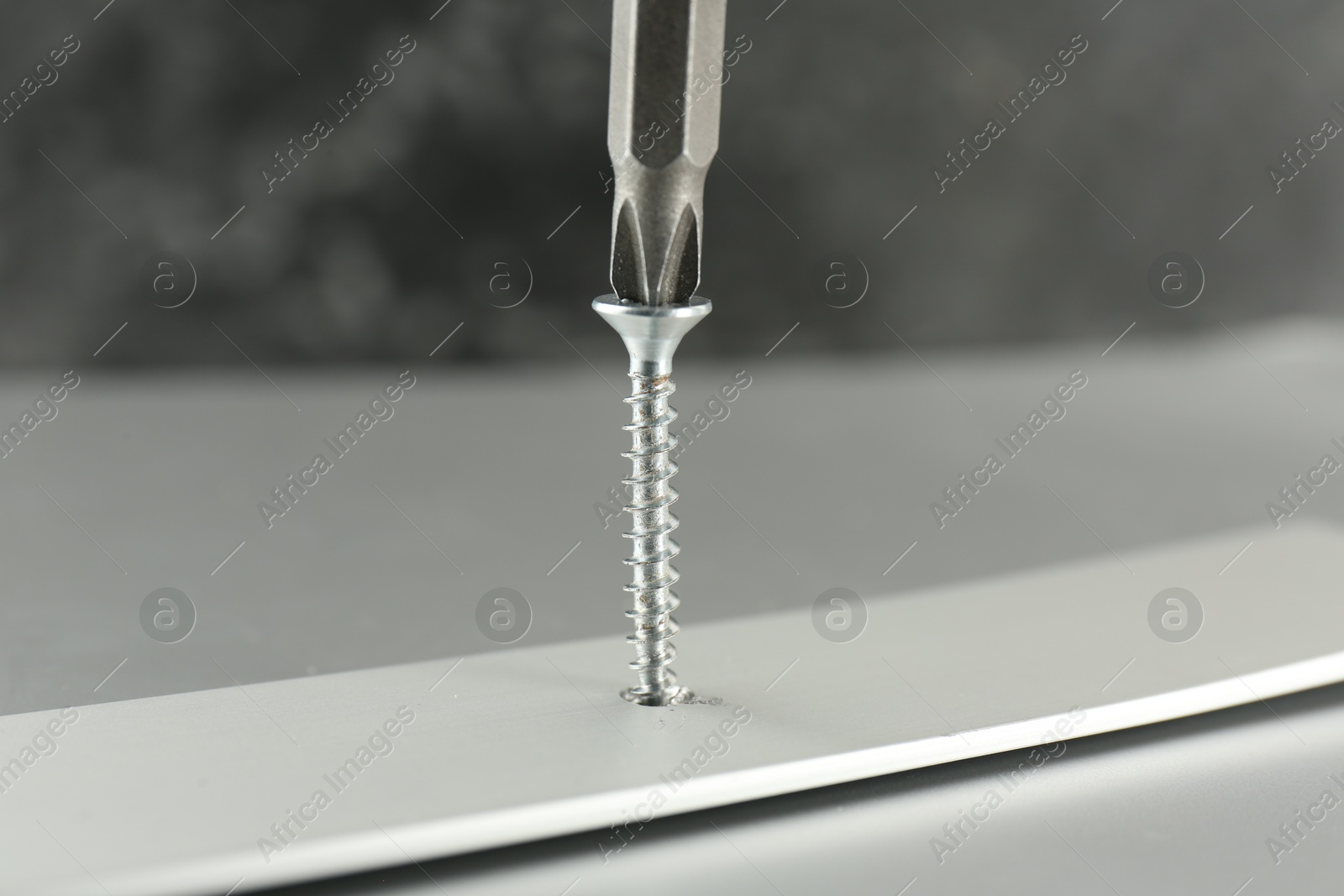 Photo of Screwing screw into white panel at light table, closeup