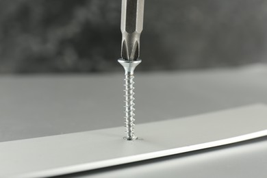 Photo of Screwing screw into white panel at light table, closeup