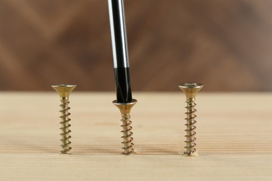 Photo of Screwing screw into wooden plank, closeup view