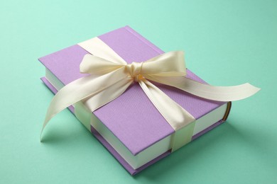 Photo of Book tied with beige ribbon on turquoise background