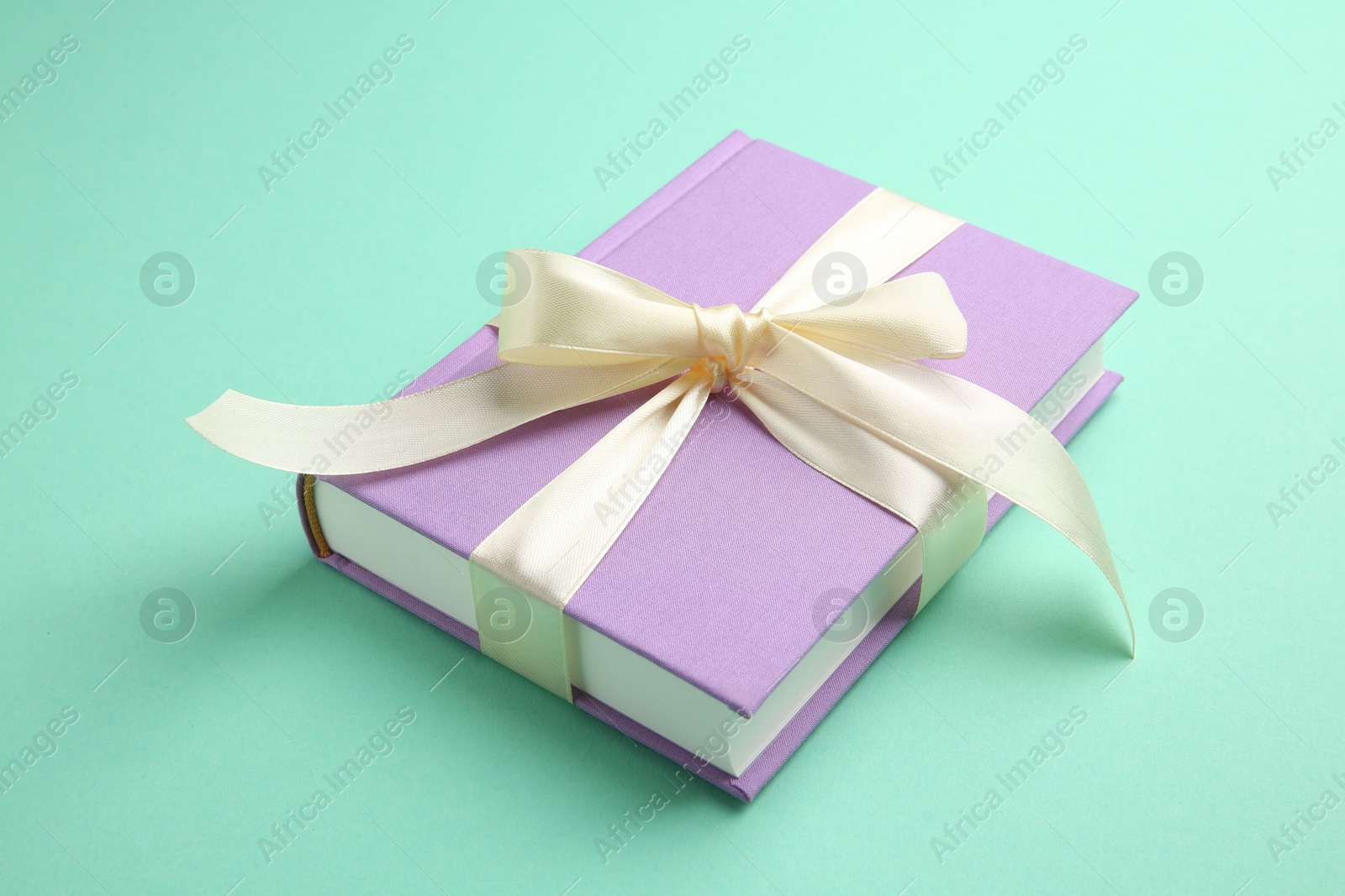 Photo of Book tied with beige ribbon on turquoise background