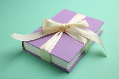 Photo of Book tied with beige ribbon on turquoise background