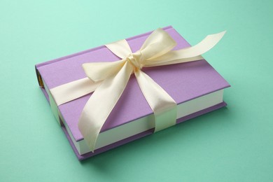 Photo of Book tied with beige ribbon on turquoise background