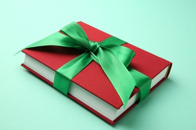 Photo of Book tied with green ribbon on turquoise background