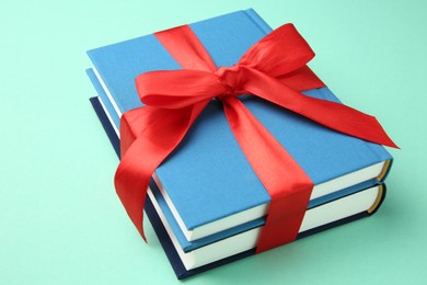 Books tied with red ribbon on turquoise background, closeup