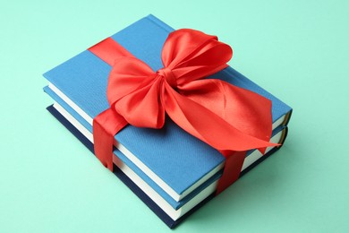 Books tied with red ribbon on turquoise background