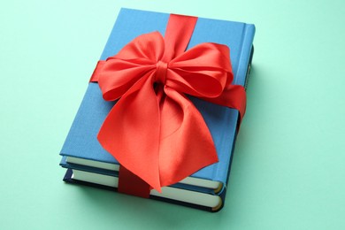 Photo of Books tied with red ribbon on turquoise background