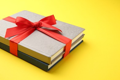 Photo of Books tied with red ribbon on yellow background, space for text