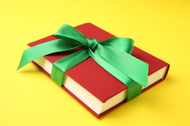 Book tied with green ribbon on yellow background