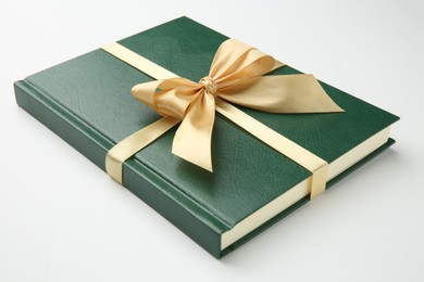 Book tied with golden ribbon on white background, closeup