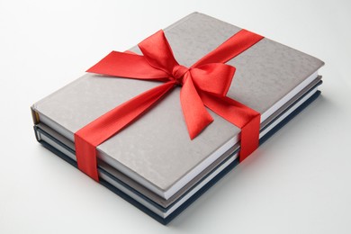 Books tied with red ribbon on white background, closeup