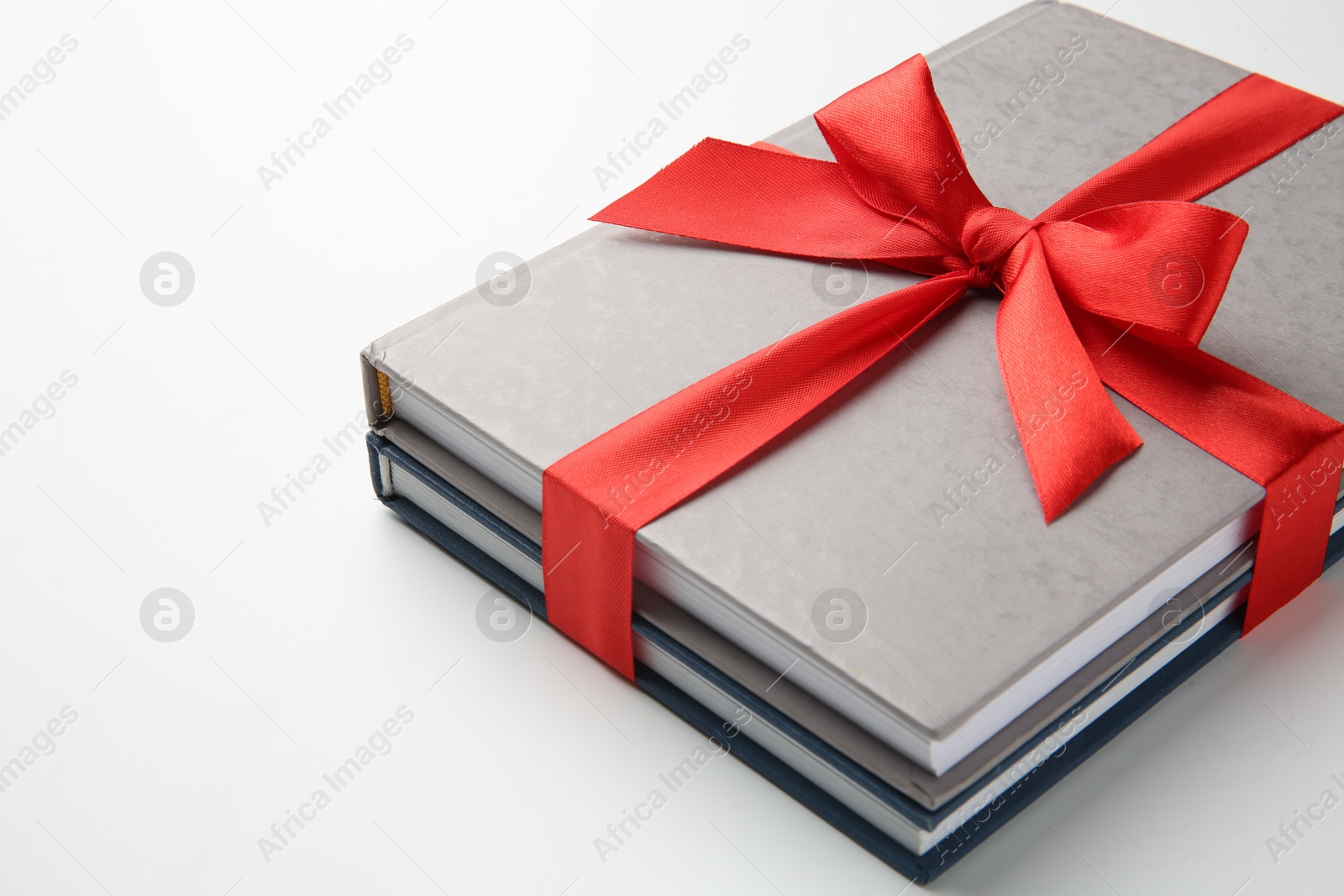 Photo of Books tied with red ribbon on white background, closeup