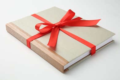 Book tied with red ribbon on white background, closeup