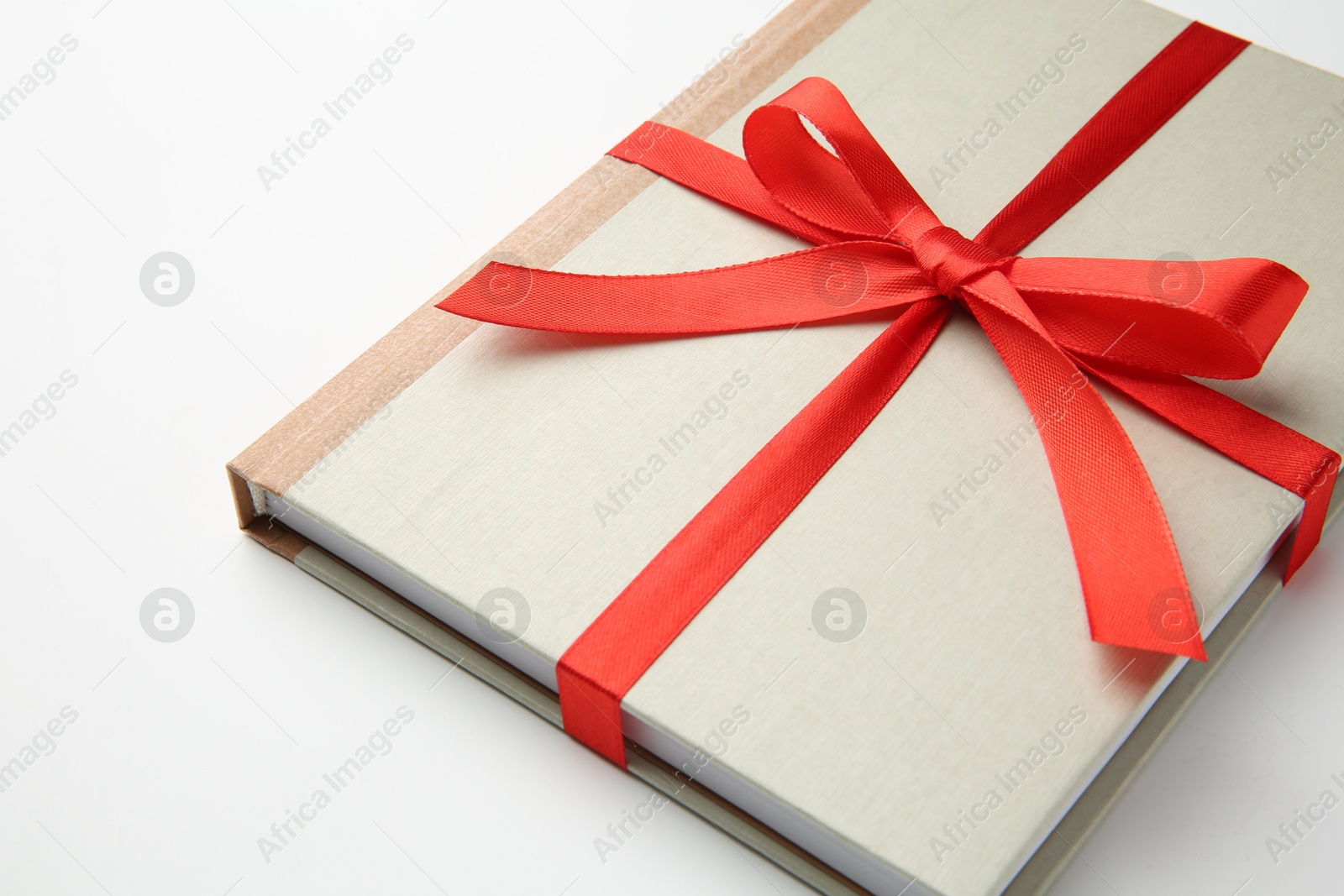 Photo of Book tied with red ribbon on white background, closeup