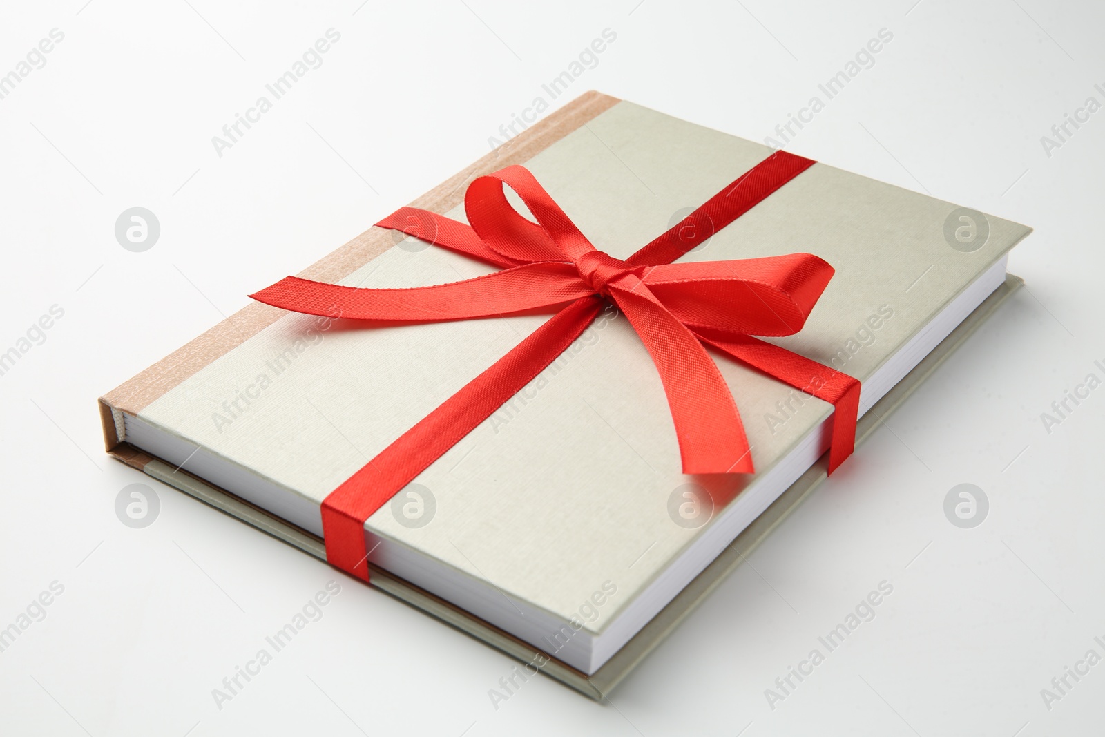 Photo of Book tied with red ribbon on white background