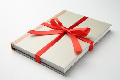 Photo of Book tied with red ribbon on white background