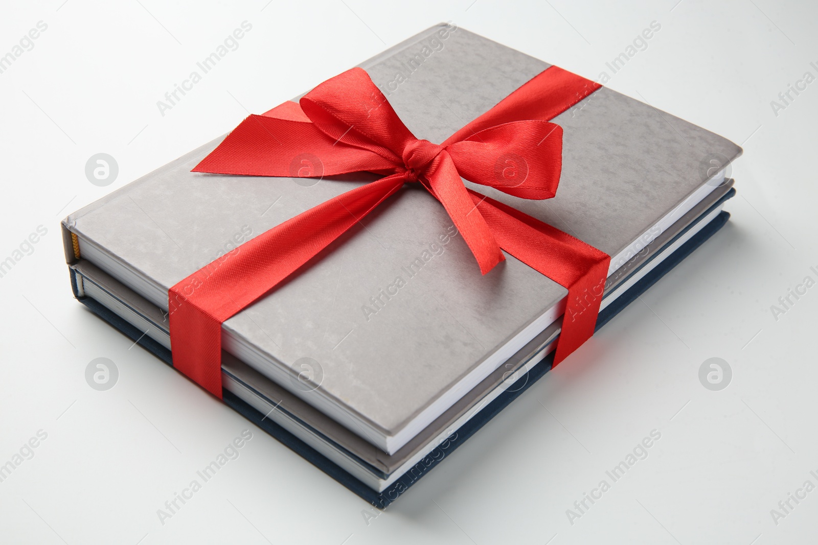 Photo of Books tied with red ribbon on white background